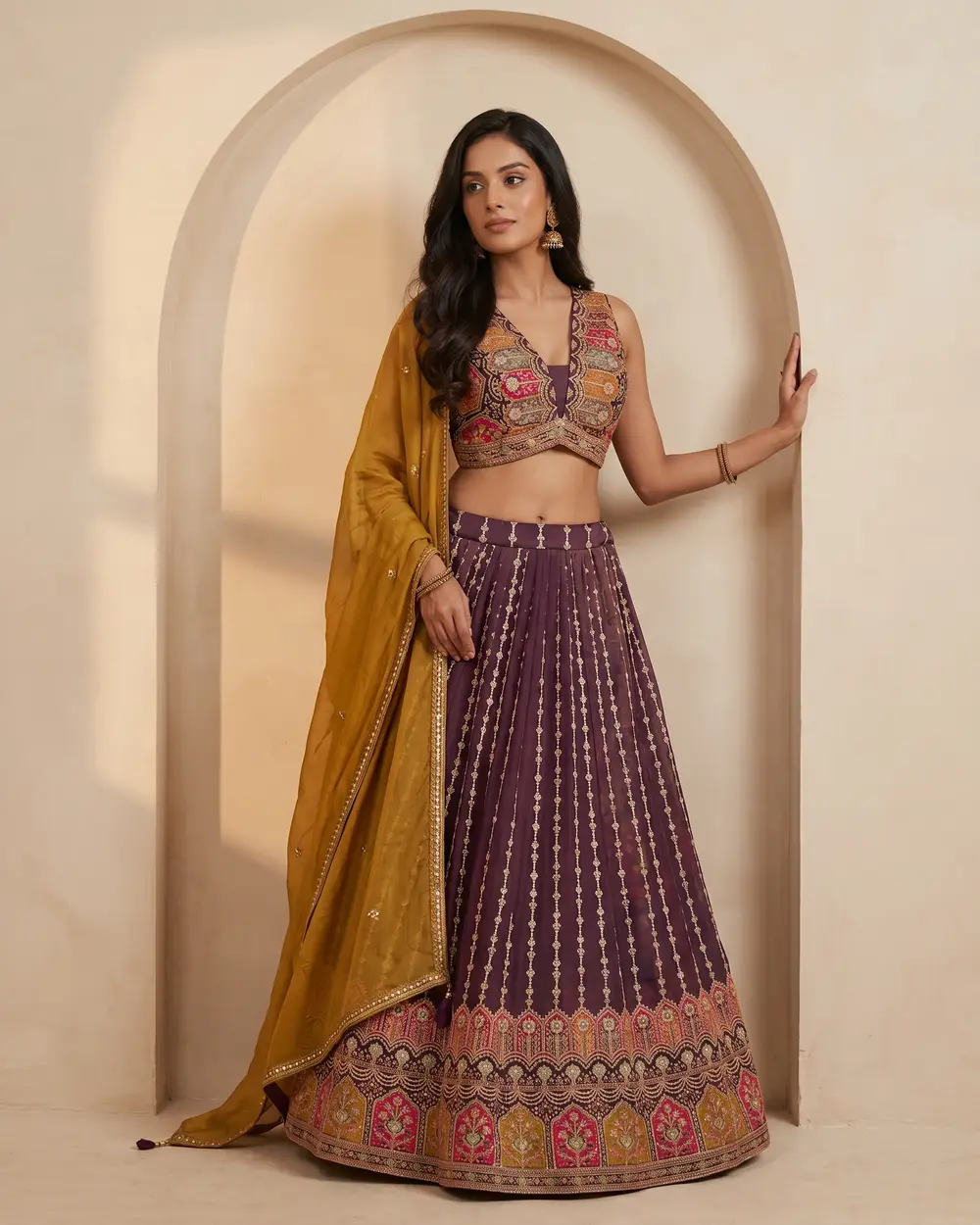Model in a plum embroidered lehenga with a mustard dupatta